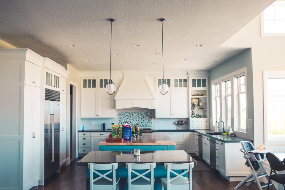 A domestic kitchen with an island, stools and daylight from a window.