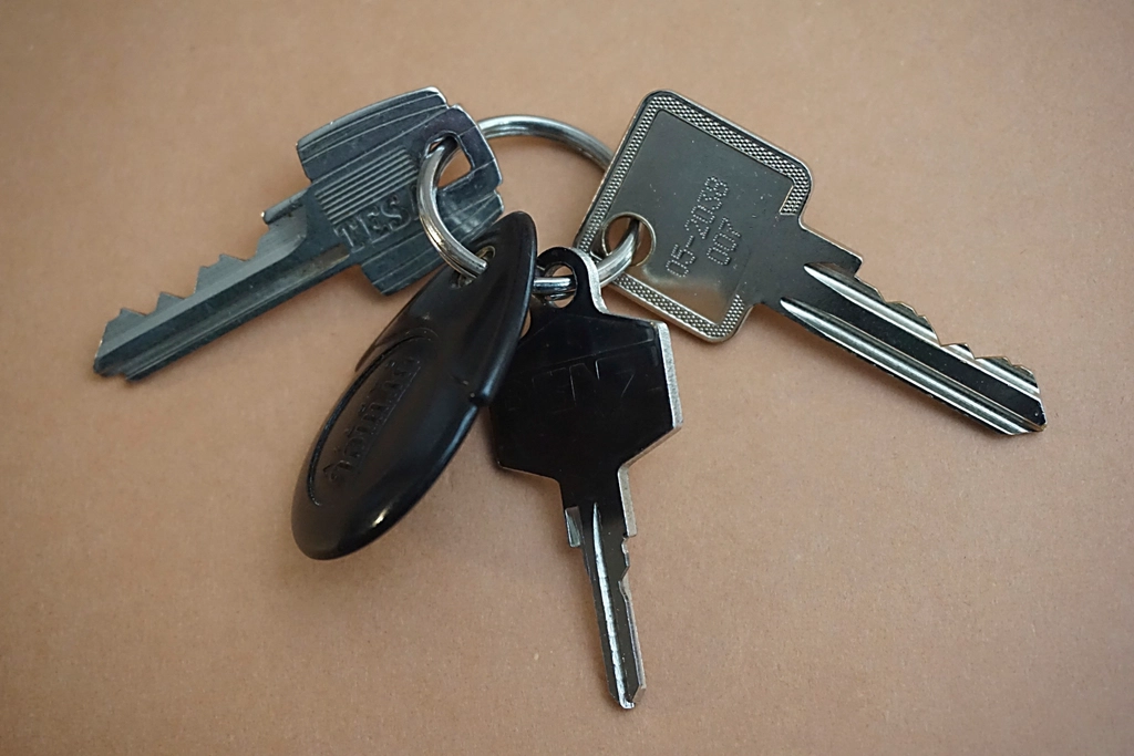 A set of keys with a keyring resting on a plain table.